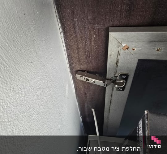 ציר מתכת מותקן על דלת ארון מטבח